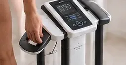 Pessoa sobre a balança de bioimpedância.